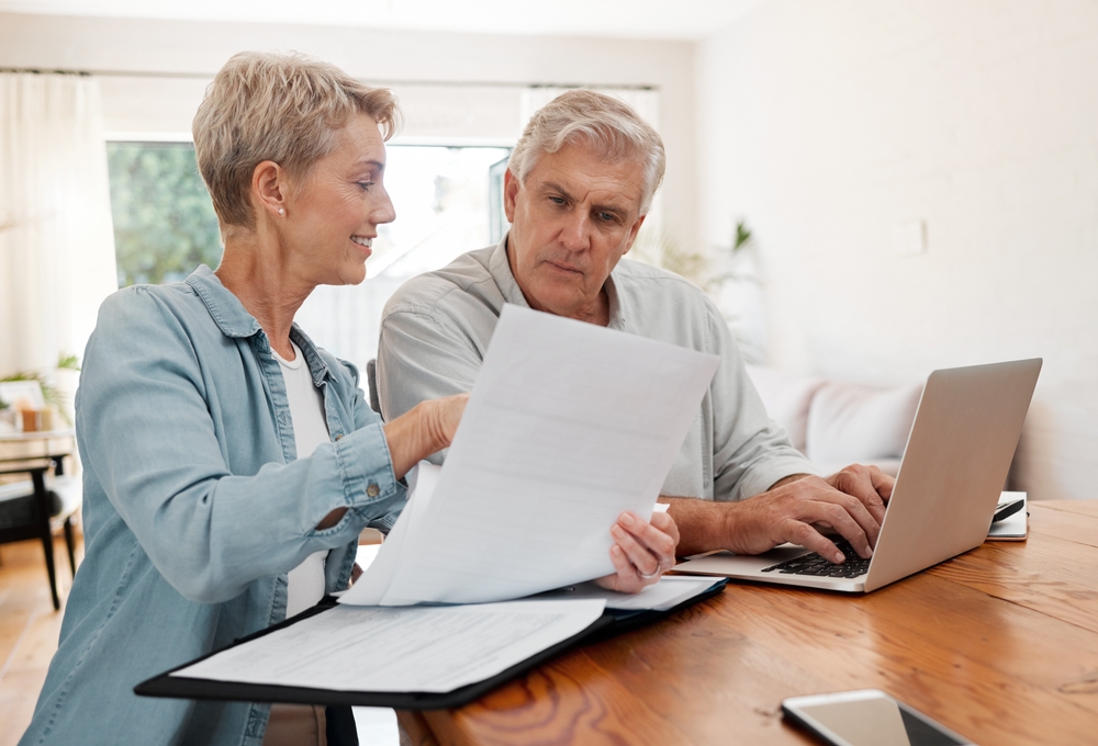Senior,Couple,,Laptop,And,Home,Finance,While,Reading,Paperwork,Documents